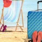 Cadeira de praia, mala, chinelos e chapéu na praia