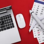 Calendário ao lado de notebook e avião em miniatura