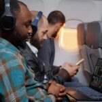 Homens sentados em assentos de classe econômica em avião