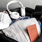 Mala aberta com fones de ouvido, tênis e passaporte