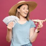 Mulher com chapéu segurando dinheiro e um avião em miniatura