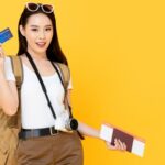 Mulher com mochila, câmera fotográfica, passagens e cartão de crédito