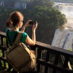 Mulher com mochila tirando foto nas Cataratas do Iguaçu