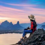 Mulher de chapéu sentada em topo de montanha