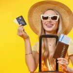 Mulher de óculos e chapéu com cartão de crédito, mala e passaporte